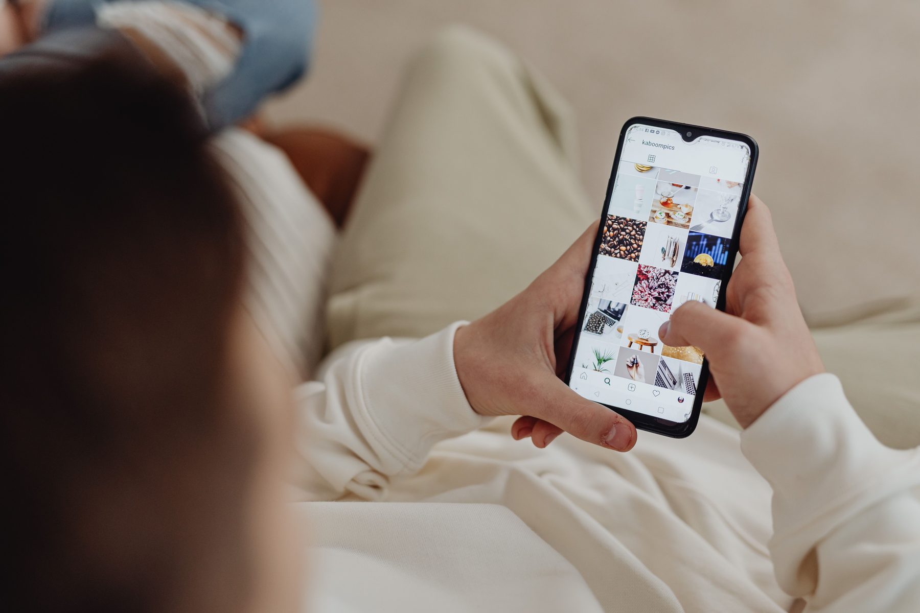 Someone scrolling an Instagram feed on their phone, screen light on their face